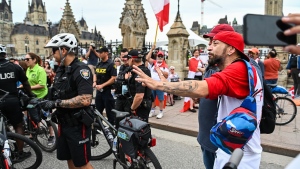 A protestor protesting against COVID-19 health measures talks to members of the Ottawa Police Service (OPS) and Ontario Provincial Police (OPP) during a demonstration in the downtown core of Ottawa, Ont. during Canada Day celebrations on Friday, July 1, 2022. THE CANADIAN PRESS/Spencer Colby