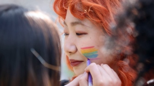Pride volunteers add rainbow face paint to each other's faces ahead of the Pride in London parade, Saturday, July 2, 2022, marking the 50th Anniversary of the Pride movement in the UK. (James Manning/PA via AP)