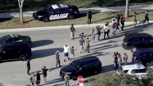 FILE - In this Feb. 14, 2018 file photo, students hold their hands in the air as they are evacuated by police from Marjory Stoneman Douglas High School in Parkland, Fla., after a shooter opened fire on the campus. The 12 jurors and 10 alternates chosen this past week to decide whether Cruz is executed will be exposed to horrific images and emotional testimony, but must deal with any mental anguish alone. (Mike Stocker/South Florida Sun-Sentinel via AP, FIle)
