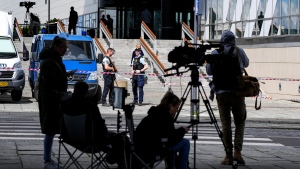 A group of journalists stand at their live position as police guards an area in front of the Field's shopping center in Copenhagen, Denmark, Monday, July 4, 2022. Danish police believe a shopping mall shooting that left three people dead and four others seriously wounded was not terror-related. They said Monday that the gunman acted alone and appears to have selected his victims at random. (AP Photo/Sergei Grits)