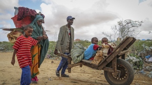 A local resident uses a wheelbarrow to transport the young children of a woman who fled drought-stricken areas as she arrives at a makeshift camp for the displaced on the outskirts of Mogadishu, Somalia Thursday, June 30, 2022. The war in Ukraine has abruptly drawn millions of dollars away from longer-running humanitarian crises and Somalia is perhaps the most vulnerable as thousands die of hunger amid the driest drought in decades. (AP Photo/Farah Abdi Warsameh)
