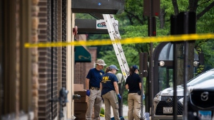 Members of the FBI's Evidence Response Team Unit investigate in downtown Highland Park, Ill., the day after a deadly mass shooting on Tuesday, July 5, 2022.   Police say the gunman who attacked an Independence Day parade in suburban Chicago fired more than 70 rounds with an AR-15-style gun.  (Ashlee Rezin /Chicago Sun-Times via AP)