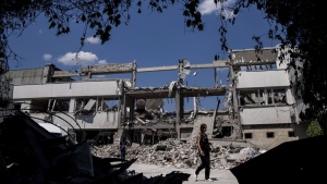 Ukrainian journalists walk in the yard of National Pedagogic university destroyed by a Russian attack in Kharkiv, Ukraine, Wednesday, July 6, 2022. (AP Photo/Evgeniy Maloletka)
