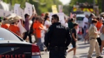 A Uvalde Police Department officer watches as family and friends of those killed and injured in the school shooting at Robb Elementary take part in a protest march and rally, July 10, 2022, in Uvalde, Texas. (AP Photo/Eric Gay)