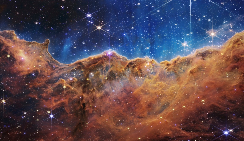 This image released by NASA on Tuesday, July 12, 2022, shows the edge of a nearby, young, star-forming region NGC 3324 in the Carina Nebula. Captured in infrared light by the Near-Infrared Camera (NIRCam) on the James Webb Space Telescope, this image reveals previously obscured areas of star birth, according to NASA. (NASA, ESA, CSA, and STScI via AP) 