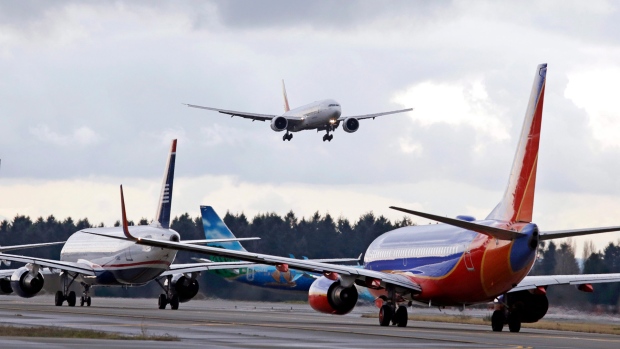In this Dec. 16, 2015 file photo, a passenger jet comes in for a landing and in view of a line of planes waiting to takeoff, at Seattle-Tacoma International Airport.  U.S. environmental regulators are moving to limit emissions from aircraft, ruling that jet engine exhaust is endangering human health by warming the planet. The Environmental Protection Agency announced Monday that it will use its authority under the Clean Air Act to regulate aircraft emissions.  (AP Photo/Elaine Thompson)