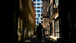 A man walks between two apartment buildings during in downtown Toronto on Thursday, June 10, 2021. THE CANADIAN PRESS/Nathan Denette