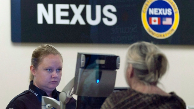 A Canada Border Services Agency officer speaks with a traveller at the Nexus office at the airport in Ottawa, in a May 8, 2012, file photo. THE CANADIAN PRESS/Adrian Wyld, File