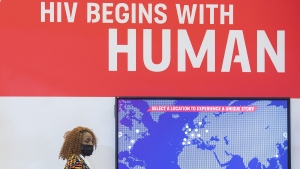A woman walks by a sign during the AIDS 2022 conference in Montreal, Sunday, July 31, 2022. THE CANADIAN PRESS/Graham Hughes