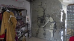 A mural by secretive British graffiti artist Banksy is covered with protective glass inside a gift shop, in the West Bank city of Bethlehem, Thursday, Aug. 4, 2022. A long-missing painting of a slingshot-toting rat by Banksy was mysteriously transferred from the occupied West Bank to the Urban Gallery in Tel Aviv. (AP Photo/Nasser Nasser)