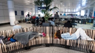 People sleep on a bench as they wait at Pierre Elliott Trudeau airport, in Montreal, Wednesday, June 29, 2022. THE CANADIAN PRESS/Ryan Remiorz