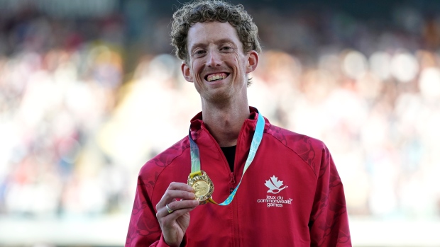 Evan Dunfee of Canada poses on the podium after winning the gold medal in the Men's 10,000 meters race walk during the athletics competition in the Alexander Stadium at the Commonwealth Games in Birmingham, England, Sunday, Aug. 7, 2022. (AP Photo/Alastair Grant)