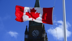 A Canadian flag is pictured with the Peace Tower on Parliament Hill in Ottawa on Monday, April 12, 2021.A new survey finds more Canadians report a strong attachment to their primary language than to other markers of identity, including the country they call home. THE CANADIAN PRESS/Sean Kilpatrick