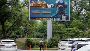 A person walks past a billboard reading " Sign up for a volunteer team" encouraging Russians to sign up for the Tiger volunteer battalion, at the far-eastern Primorye region in a street of Vladivostok, Russia, Thursday, Aug. 11, 2022. Colorful billboards and ads on public transport in different Russian regions state that "heroes are wanted" and urge Russian men to join the professional army ranks. (AP Photo)