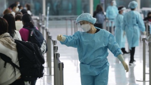 FILE - Workers wearing protective gear direct arriving passengers to quarantine hotels in the Hong Kong International Airport, Friday, April 1, 2022. Hong Kong’s government says its population has shrunk for a second year as anti-virus controls hampered the inflow of new workers and births declined, but it made no mention of an exodus of residents following a crackdown on a pro-democracy movement. (AP Photo/Kin Cheung, File)