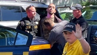 Law enforcement officers detain Hadi Matar, 24, of Fairview, N.J., outside the Chautauqua Institution, Friday, Aug. 12, 2022, in Chautauqua, N.Y.. Salman Rushdie, the author whose writing led to death threats from Iran in the 1980s, was attacked and apparently stabbed in the neck Friday by Matar who rushed the stage as he was about to give a lecture at the institute in western New York. (Charles Fox via AP)