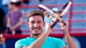 Pablo Carreno Busta, of Spain, hoists the trophy as he celebrates after defeating Hubert Hurkacz, of Poland, in the final of the National Bank Open tennis tournament in Montreal on Sunday, August 14, 2022. THE CANADIAN PRESS/Paul Chiasson