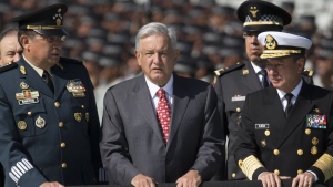Mexican President Andres Manuel Lopez Obrador, flanked by Defense Secretary Gen. Luis Crescencio Sandoval, left, and Marine Secretary Jose Rafael Ojeda, surveys National Guard troops as the new force is presented at a ceremony, in Mexico City, June 30, 2019. Lopez Obrador has begun exploring plans to side-step congress to hand formal control of the National Guard to the army. That has raised concerns, because he won approval for creating the force in 2019 by pledging in the constitution that it would be under nominal civilian control and that the army would be off the streets by 2024. (AP Photo/Christian Palma, File)