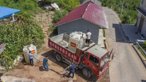 In this photo released by Xinhua News Agency, workers transfer water from a drought relief water truck to residents in Luoping village of Wushan County in southwestern China's Chongqing, Saturday, Aug. 13, 2022. Unusually high temperatures and a prolonged drought are affecting large swaths of China, affecting crop yields and drinking water supplies for thousands of people. (Huang Wei/Xinhua via AP)