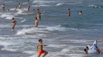 People cool off on Puerto de Sagunto beach, east Spain on Tuesday, Aug. 16, 2022. While vacationers might enjoy the Mediterranean sea’s summer warmth, climate scientists are warning of dire consequences for its marine life as it burns up in a series of severe heat waves. (AP Photo/Alberto Saiz)