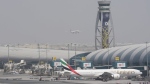An Emirates Boeing 777 stands at the gate at Dubai International Airport as another prepares to land on the runway in Dubai, United Arab Emirates, Wednesday, Aug. 17, 2022. Dubai International Airport saw a surge in passengers over the first half of 2022 as pandemic restrictions eased and the upcoming FIFA World Cup in Qatar will further boost traffic to the city-state's second airfield, its chief executive said Wednesday. (AP Photo/Jon Gambrell)
