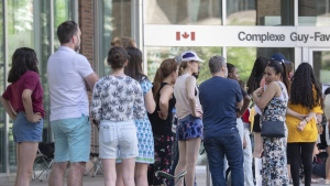 The federal government is adding new passport service locations across Canada as a loud backlash over long wait times continues. People line up outside the Guy Favreau federal building while waiting to apply for a passport in Montreal, Sunday, June 26, 2022. THE CANADIAN PRESS/Graham Hughes