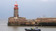 Water police drive past the leaning Mole tower in Bremerhaven, Germany, Thursday, Aug. 18, 2022. Officials in Bremen said Thursday that an iconic lighthouse at the German city’s port has tilted sideways and could soon topple over entirely. (Sina Schuldt/dpa via AP)
