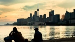 People sit and watch storm clouds passing by the skyline in Toronto on Tuesday, June 8, 2021. THE CANADIAN PRESS/Frank Gunn