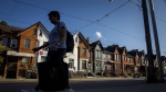 A person walks by a row of houses in Toronto on Tuesday July 12, 2022. THE CANADIAN PRESS/Cole Burston