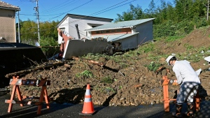 A worker places a barricade at the scene of a landslide that damaged a residential area in Hamamatsu of the Shizuoka prefecture, central Japan, Saturday, Sept. 24, 2022. Tropical Depression Talas unleashed fierce rainfall Saturday in parts of Japan, setting off landslides, halting trains and killing a man after he crashed his car into a pond. (Mizuki Ikari/Kyodo News via AP)