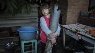 Veronika Tkachenko, 7, holds a piece of a Grad rocket which hit her family's house in the recently retaken town of Izium, Ukraine, Sunday, Sept. 25, 2022. (AP Photo/Evgeniy Maloletka)