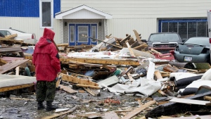 A Canadian Forces Ranger examines damage to a home in Port aux Basques, N.L., Monday, Sept. 26, 2022. Across the Maritimes, eastern Quebec and in southwestern Newfoundland, the economic impact of post-tropical storm Fiona’s wrath is still being tallied. THE CANADIAN PRESS/Frank Gunn