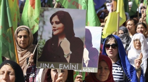 In this photo provided by Kurdish-run Hawar News Agency, Kurdish women hold portraits of Iranian Mahsa Amini, during a protest condemning her death in Iran, in the city of Qamishli, northern Syria, Monday, Sept. 26, 2022. Protests have erupted across Iran in recent days after Amini, a 22-year-old woman, died while being held by the Iranian morality police for violating the country's strictly enforced Islamic dress code. (Hawar News Agency via AP via AP)