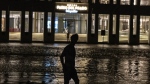 A man walks through a flooded street in front of a hotel powered by an oil generator during a blackout in Havana, Cuba, Wednesday, Sept. 28, 2022. Cuba remained in the dark early Wednesday after Hurricane Ian knocked out its power grid and devastated some of the country's most important tobacco farms when it hit the island's western tip as a major storm. (AP Photo/Ramon Espinosa)