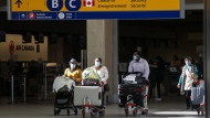 Passengers wear masks at Calgary International Airport in Calgary, Alta., on Friday, Oct. 30, 2020.  THE CANADIAN PRESS/Jeff McIntosh