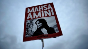 A woman holds a placard with a picture of Iranian Mahsa Amini as she attends a protest against her death, in Berlin, Germany, Wednesday, Sept. 28, 2022. Amini, a 22-year-old woman who died in Iran while in police custody, was arrested by Iran's morality police for allegedly violating its strictly-enforced dress code. (AP Photo/Markus Schreiber)