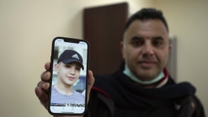 FILE - Muamar Nakhleh, father of Amal Nakhleh, a Palestinian teen with a rare neuromuscular disorder, who had been held without charge for a year, shows his photo at his office, in the West Bank city of Ramallah, Jan, 10, 2022. He was released in May 2022. HaMoked, an Israeli rights group said Sunday, Oct. 2, 2022, that Israel is holding nearly 800 Palestinians without trial or charge in so-called administrative detention, the highest number since 2008. Under the practice, prisoners can be held for months, do not know the charges against them and are not granted access to the evidence against them. (AP Photo/Majdi Mohammed, File)