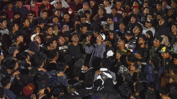 Soccer fans chant slogans during vigil for the victims of Saturday's soccer riots, in Malang, East Java, Indonesia, Sunday, Oct. 2, 2022. Police firing tear gas after an Indonesian soccer match in an attempt to stop violence triggered a disastrous crush of fans making a panicked, chaotic run for the exits, leaving a large number of people dead, most of them trampled upon or suffocated. (AP Photo/Dicky Bisinglasi)