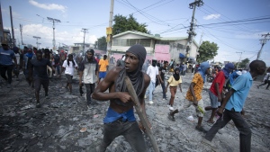 A protester carries a piece of wood simulating a weapon during a protest demanding the resignation of Prime Minister Ariel Henry, in the Petion-Ville area of Port-au-Prince, Haiti, Monday, Oct. 3, 2022. (AP Photo/Odelyn Joseph)