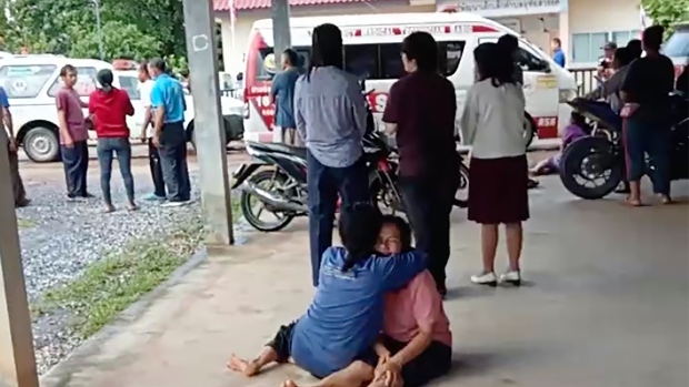 In this image taken from video, a distraught woman is comforted outside the site of an attack at a daycare center, Thursday, Oct. 6, 2022, in the town of Nongbua Lamphu, north eastern Thailand. More than 30 people, primarily children, were killed Thursday when a gunman opened fire in the childcare center authorities said. (Mungkorn Sriboonreung Rescue Group via AP)