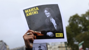 A protester shows a portrait of Mahsa Amini during a demonstration to support Iranian protesters standing up to their leadership over the death of a young woman in police custody, Sunday, Oct. 2, 2022 in Paris.  (AP Photo/Aurelien Morissard)