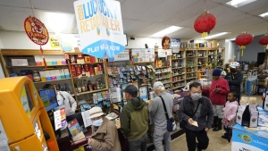 Madeline Copper, second from right, and her granddaughter, Lay-Lonnie, 5, stand in line to buy Powerball lottery tickets at the Wo Won Mini market in the Chinatown district of Los Angeles, Monday, Nov. 7, 2022. Monday night's estimated $1.9 billion Powerball jackpot is nearly $400 million larger than the previous record jackpot. (AP Photo/Damian Dovarganes)