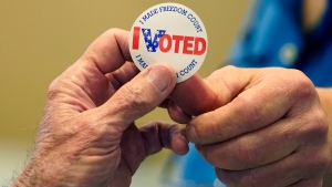 Gary Wilson, right, a poll worker in a Rankin County precinct, hands an "I Voted" sticker to a person who filled out a ballot Tuesday, Nov. 8, 2022. (AP Photo/Rogelio V. Solis)