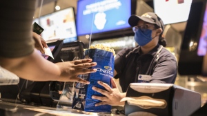 A Cineplex employee serves customers popcorn and other snacks at a Cineplex theatre in Toronto on Wednesday, Aug. 26, 2020. THE CANADIAN PRESS/Christopher Katsarov