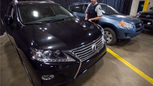 RCMP Investigator Maxime Deschenes looks at a stolen Lexus that was seized from a container at a news conference Thursday, July 17, 2014 in Montreal. THE CANADIAN PRESS/Ryan Remiorz