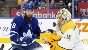Nashville Predators goaltender Juuse Saros stops a shot as Toronto Maple Leafs defenceman Jake Muzzin (8) skates in during second period NHL hockey action in Toronto, Tuesday, Nov. 16, 2021. The Leafs will be without Muzzin for at least the next three months. THE CANADIAN PRESS/Chris Young