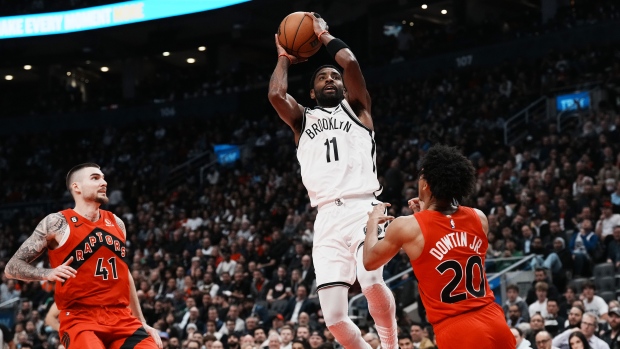 Brooklyn Nets guard Kyrie Irving (11) scores over Toronto Raptors guard Jeff Dowtin Jr. (20) as Raptors forward Juancho Hernangomez (41) looks on during second half NBA basketball action in Toronto on Wednesday, November 23, 2022. THE CANADIAN PRESS/Chris Young