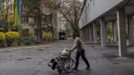 A man uses a wheelchair to transport water to a hospital in Kherson, southern Ukraine, Friday, Nov. 25, 2022. (AP Photo/Bernat Armangue)