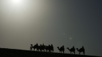 People ride camels in Mesaieed, Qatar, Nov. 26, 2022. Throngs of World Cup fans in Qatar looking for something to do between games are leaving Doha for a classic Gulf tourist experience: riding a camel in the desert. (AP Photo/Ashley Landis)