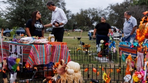 Sandra Cruz Torres, mother of Robb Elementary massacre victim Eliahna Torres, chats with Beto O'Rourke, Democratic candidate running for governor, as Cruz and her family celebrate Día de los Muertos at Torres' gravesite in Hillcrest Memorial Cemetery in Uvalde, Texas, Nov. 2, 2022. Sandra Cruz Torres filed a federal lawsuit on Monday, Nov. 28, against the police, the school district and the maker of the gun used in the massacre. (Sam Owens/The San Antonio Express-News via AP, File)